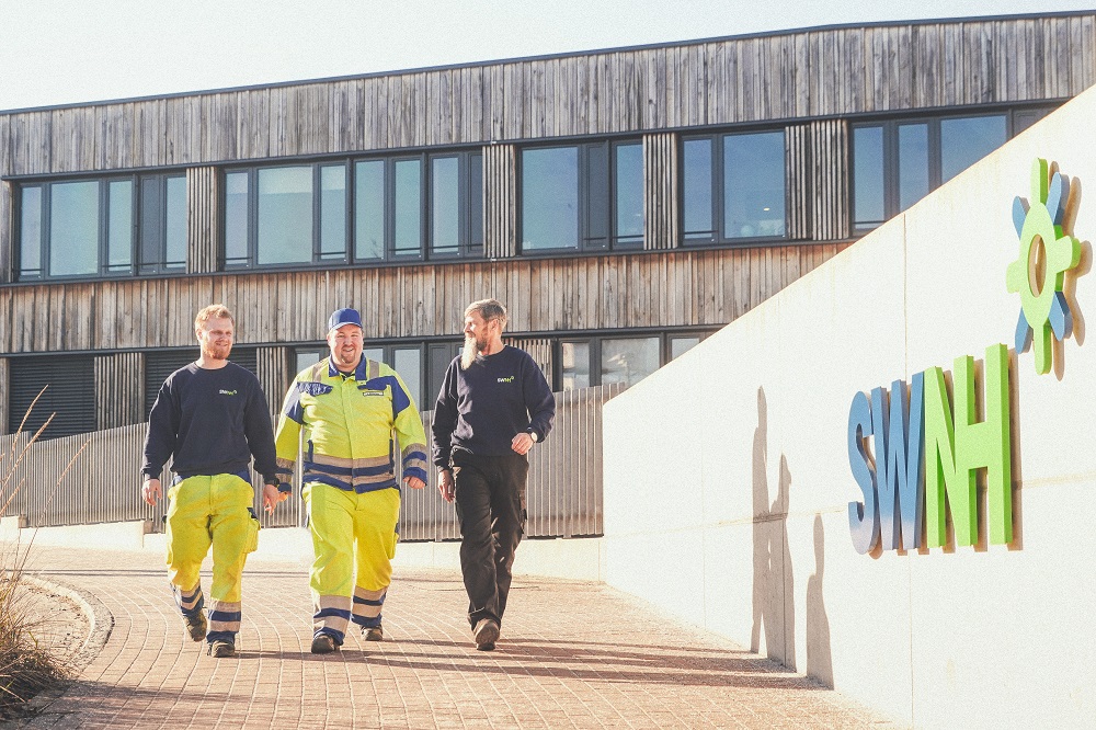 Drei Mitarbeiter gehen vor dem Verwaltungsgebäude der SWNH her
